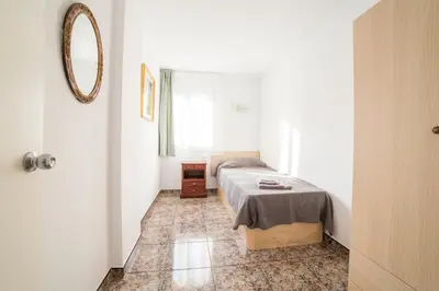 a small bedroom with a bed and a mirror at CUNIT HOME in Cunit