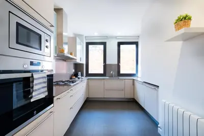 a large kitchen with white cabinets and a microwave at Petit Luxe Tobella Esquerra in Terrassa