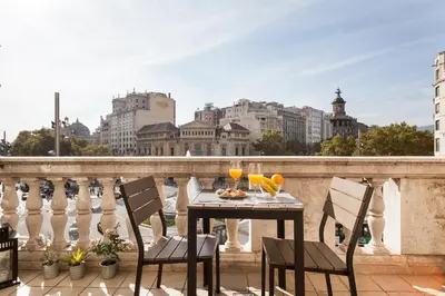 a table and chairs on a balcony with a view of the city at Uma Suites Passeig de Gracia 16 in Barcelona