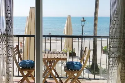 a balcony with a table and chairs and the beach at Port alegre - en el corazón de Sitges in Sitges