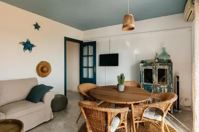 a living room with a wooden table and wicker chairs at Port alegre - en el corazón de Sitges in Sitges