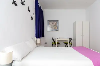 a bedroom with a white bed and a table with chairs at Monrooms Barcelona in Barcelona