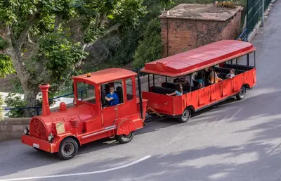 a small red train with people riding in it at Camping Roca Grossa in Calella