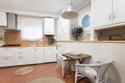a kitchen with white cabinets and a table and chairs at La Casita - centro histórico y playa in Sitges