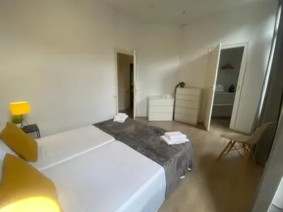 a bedroom with a large white bed and a chair at 555 Apartments BCN in Barcelona