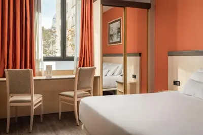 a hotel room with a bed and a desk with chairs at Petit Palace Trencadís in Barcelona