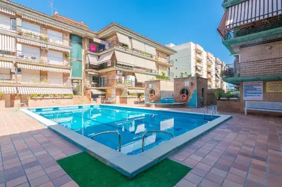 a swimming pool in front of a building at HomeHolidaysRentals Frida in Pineda de Mar