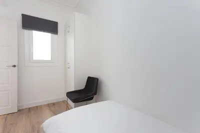 a bedroom with a black chair and a bed at Casa Cosi - Atico in Barcelona