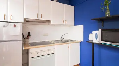 a kitchen with white cabinets and a sink and a microwave at Sunny Apartments in Sitges