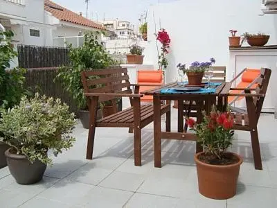 a patio with a table and chairs and potted plants at Sunny Apartments in Sitges