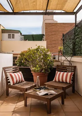 two benches and a table on a balcony with plants at BYPILLOW House in Barcelona