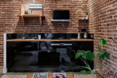 a kitchen with a black counter and a brick wall at Brummell Apartments Eixample Izquierda/Valeris in Barcelona