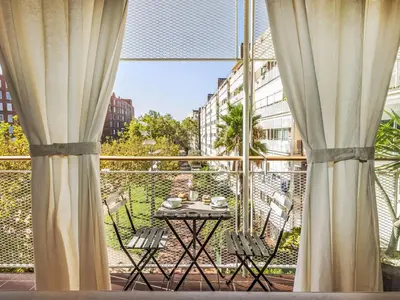 a table and chairs on a balcony with curtains at Apartment Vila Olimpica Sant Marti by Interhome in Barcelona