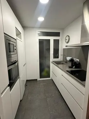 a kitchen with white cabinets and a clock on the wall at Apartment Eixample Dret Aragon - Sardenya in Barcelona