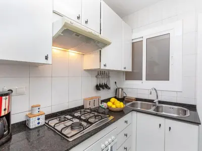 a white kitchen with a sink and a stove at Apartment Eixample Esq Rocafort Diputacio by Interhome in Barcelona