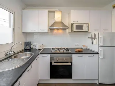 a white kitchen with a sink and a stove at Apartment Blaumar by Interhome in Sant Andreu de Llavaneres