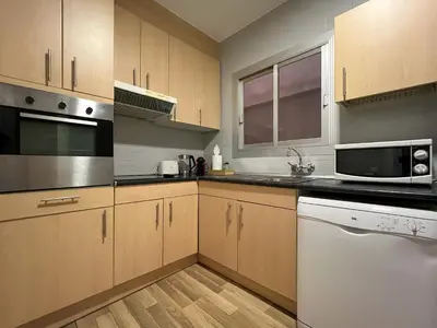 a kitchen with wooden cabinets and a white appliance at Stay U-nique Apartments Sardenya II in Barcelona