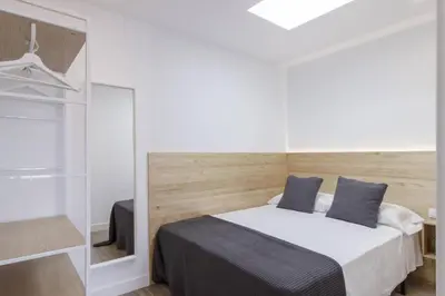 a bedroom with a bed with two blue pillows at Ola Living Camp Nou in Hospitalet de Llobregat