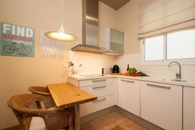 a kitchen with white cabinets and a wooden table at BCN Apartments 41 in Barcelona