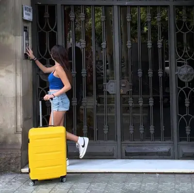 a woman is pulling a yellow suitcase in front of a door at Wow Hostel Barcelona in Barcelona