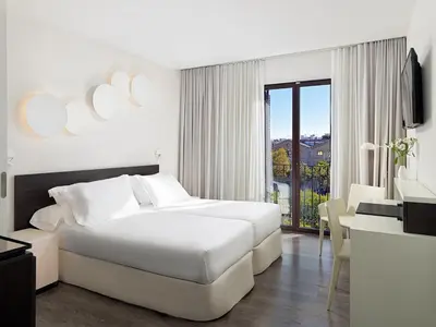 a white bedroom with a white bed and a desk at H10 Port Vell 4* Sup in Barcelona