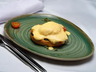 a green plate with a pastry with cheese on it at H10 Port Vell 4* Sup in Barcelona