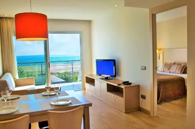 a hotel room with a bed and a desk with a television at Apartaments Maritim in Castelldefels