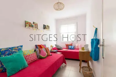 a room with two beds and a red couch at Con patio y a 5 minutos de la playa in Sitges