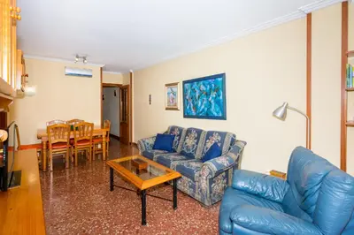 a living room with a blue couch and a table at HomeHolidaysRentals Keyla in Pineda de Mar