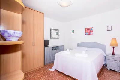 a bedroom with a white bed and a cabinet at HomeHolidaysRentals Keyla in Pineda de Mar