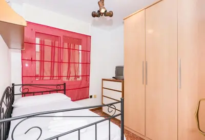 a bedroom with a bed and a red window at HomeHolidaysRentals Keyla in Pineda de Mar
