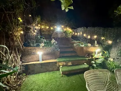 a garden at night with lights on a brick wall at casa en Masnou junto a playa y tren in Masnou