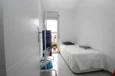 a white bedroom with a bed and a window at casa en Masnou junto a playa y tren in Masnou