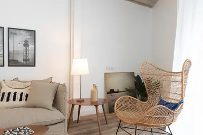 a living room with a rattan chair and a couch at En Casa de Calders 5 in Barcelona