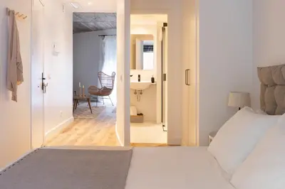a bedroom with a bed and a hallway with a chair at En Casa de Calders 5 in Barcelona