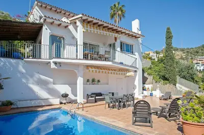 a villa with a swimming pool and a house at HOUSE WITH AMAZING VIEWS , OVERLOOKING THE FESTIVAL TOWN OF SITGES in Sitges