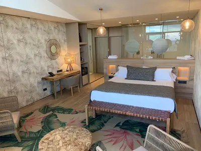 a bedroom with a large bed and a desk and a table at Playa Grande by Tropical in Gavà