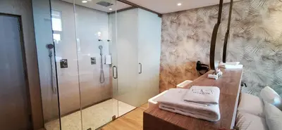 a bathroom with a shower and towels on a counter at Playa Grande by Tropical in Gavà