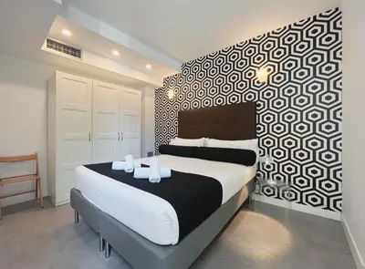 a bedroom with a bed with a black and white patterned wall at Stay U-nique Apartments Pellaires in Barcelona