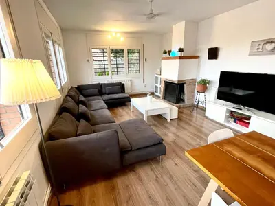 a living room with a brown couch and a television at CASA PARAÍSO PISCINA TRANQUILIDAD in Sant Cebrià de Vallalta