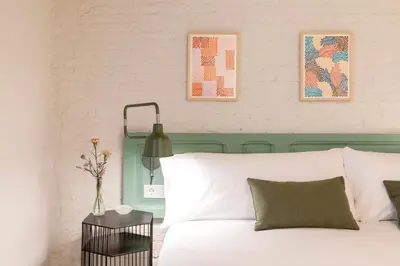 a bedroom with a white bed with a green headboard at Aspasios Gracia Apartments in Barcelona