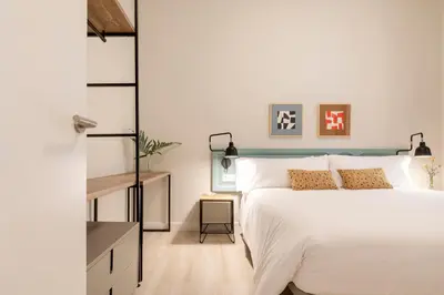 a bedroom with a white bed with a blue headboard at Aspasios Gracia Apartments in Barcelona