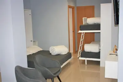 a room with two bunk beds and two chairs at Alguera Hola Apartments in Barcelona