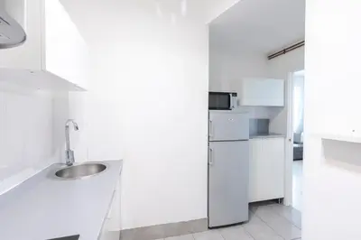 a white kitchen with a sink and a refrigerator at Nordic apartment Sagrada Familia in Barcelona