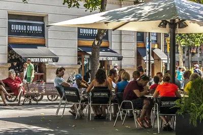 a group of people sitting at tables under an umbrella at Habitat Apartments Rambla Deluxe in Barcelona