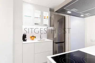 a kitchen with white cabinets and a stainless steel refrigerator at Magnificas vistas al mar in Sitges