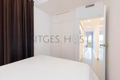 a bedroom with a white bed and a sliding glass door at Magnificas vistas al mar in Sitges