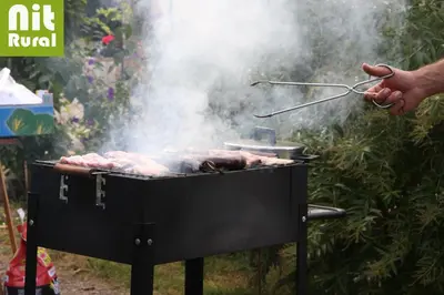 a person is cooking meat on a grill at Ca L'Estrada in Sant Esteve de Palautordera