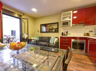 a kitchen and living room with a glass table at RamblasRentals Cozy Renovated 2BR with Balcony Lift 20M Rambla - Parking - Wifi in Barcelona