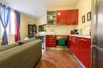 a kitchen with red cabinets and a couch in a room at RamblasRentals Design Renovated Apartment AC Balcony10m Ramblas - Parking - Wifi in Barcelona